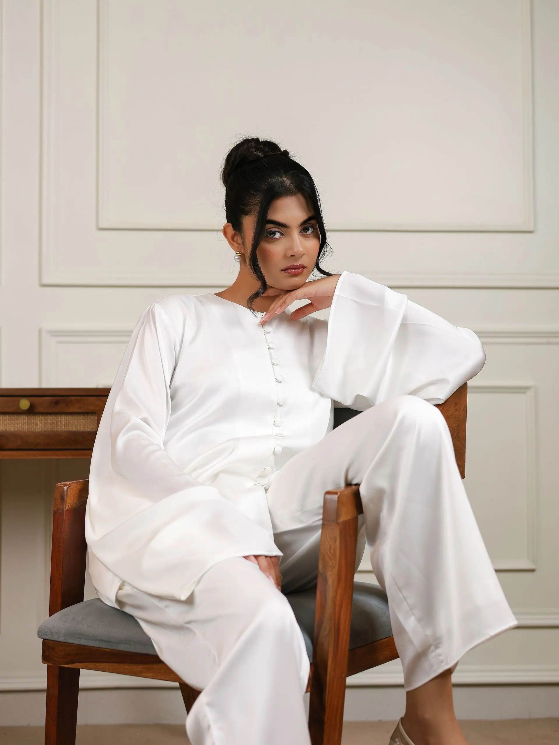 White satin co-ord, seated on a cane chair